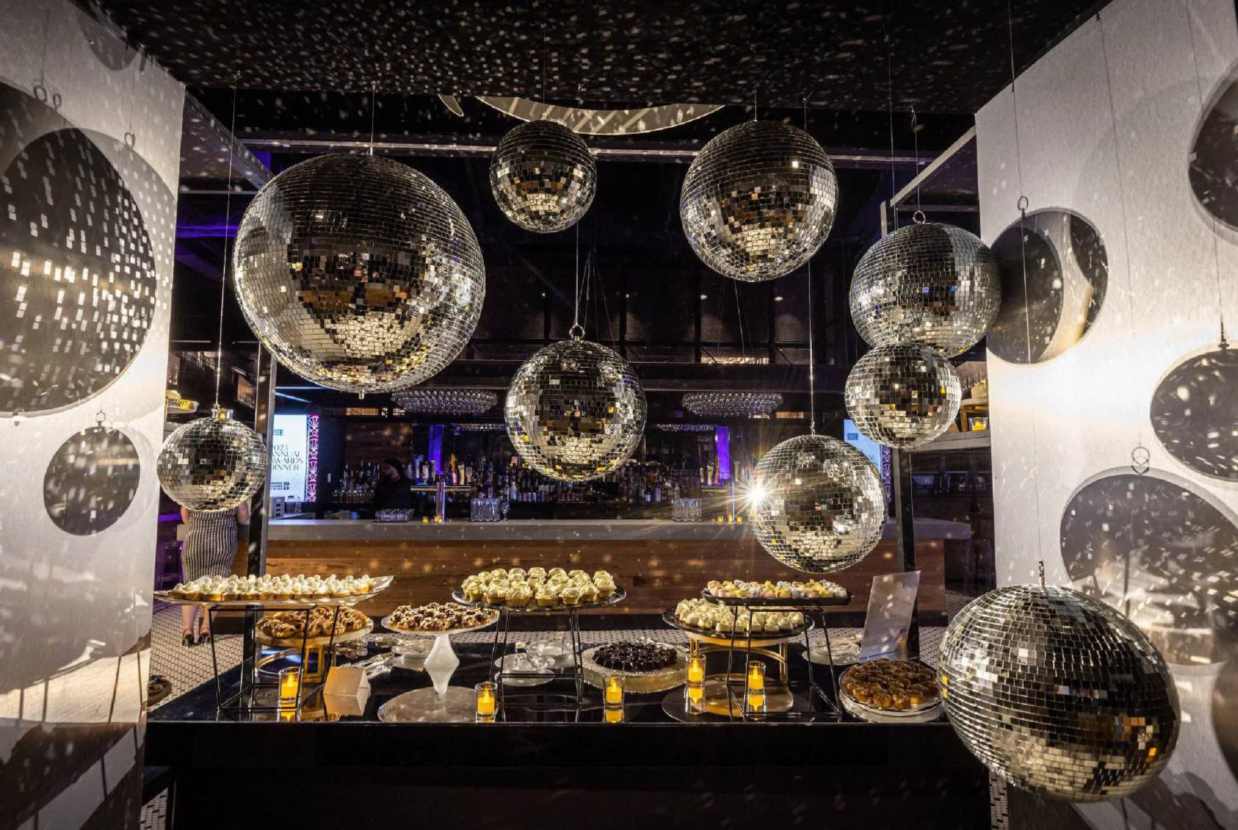 Disco balls of varying sizes dangle above a table of hors d'oeuvres.