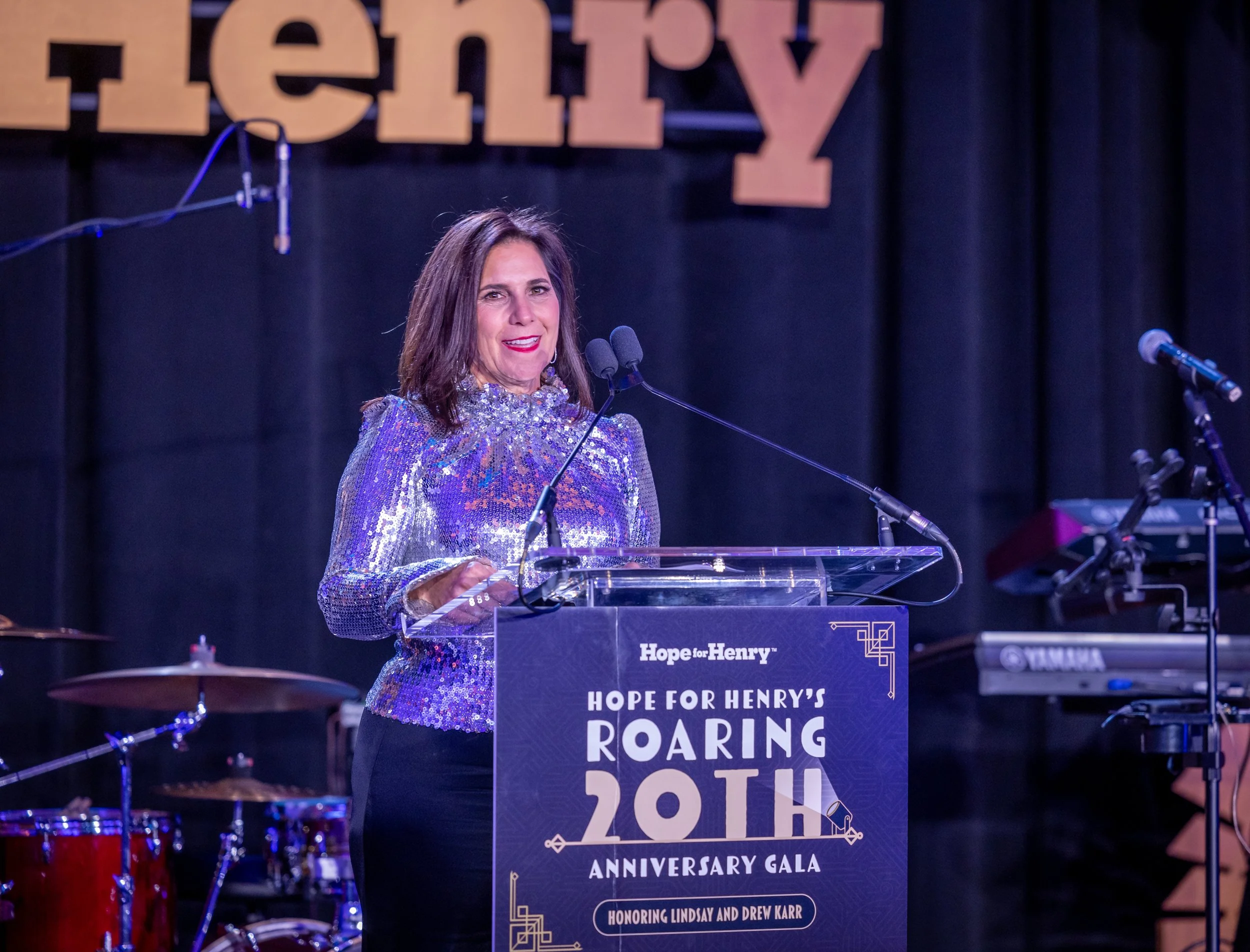 A woman speaks at a podium at Hope for Henry's Roaring 20th Anniversary Gala.