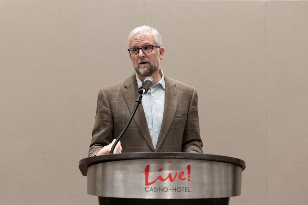 A man speaks at the podium at the 2025 Bozzuto Leadership Conference.