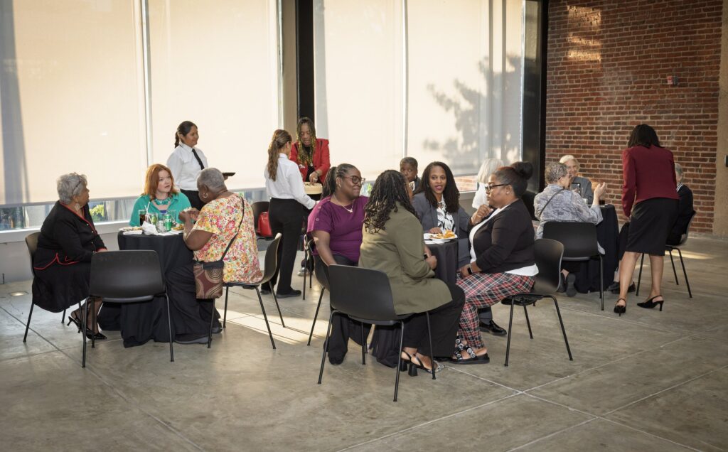 Event attendees chat at tables over a meal at N Street Village's 2025 "Meeting the Moment" event.