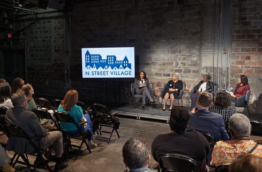 Event attendees listen to panelists onstage at N Street Village's 2025 "Meeting the Moment" event.