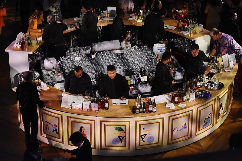 A round mega bar with several bartenders preparing to serve guests at the Embassy Chef Challenge event. Event produced by Stratus Firm, an event production company in DC