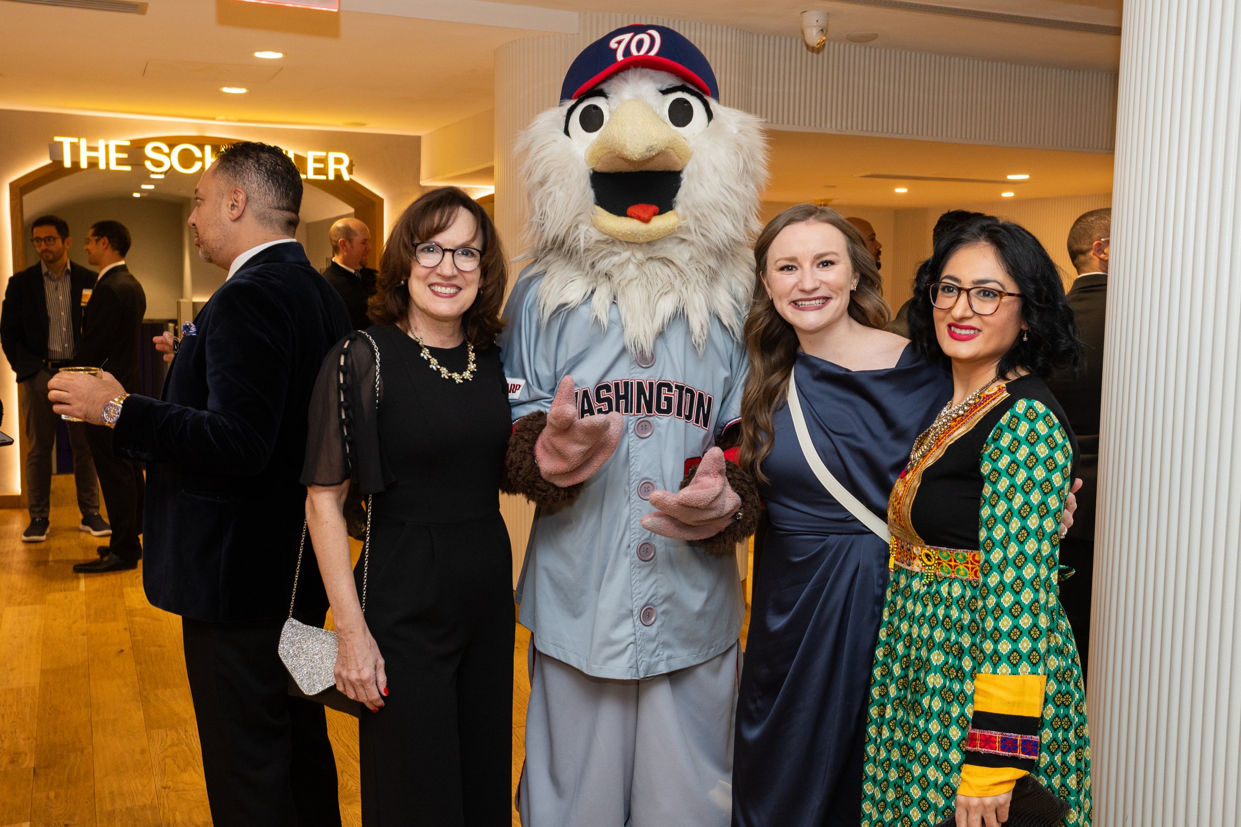 Screech, the Washington Nationals' bald eagle mascot, poses with three women for a photo at the 2025 Play for Good Gala