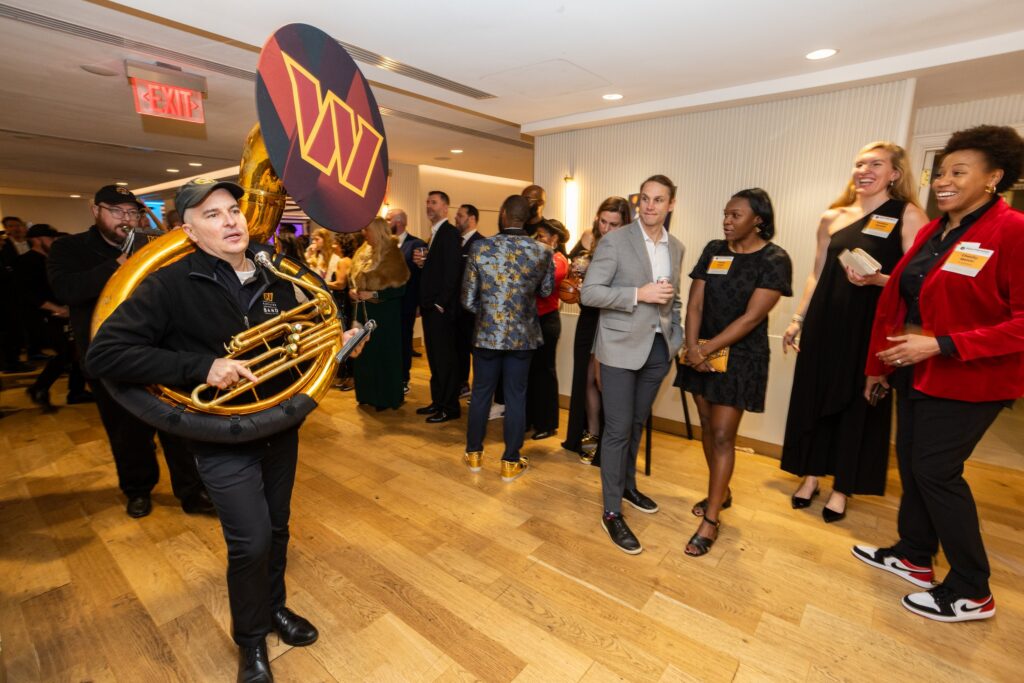 A band marches through the event space, delighting onlookers, at the 2025 Play for Good Gala
