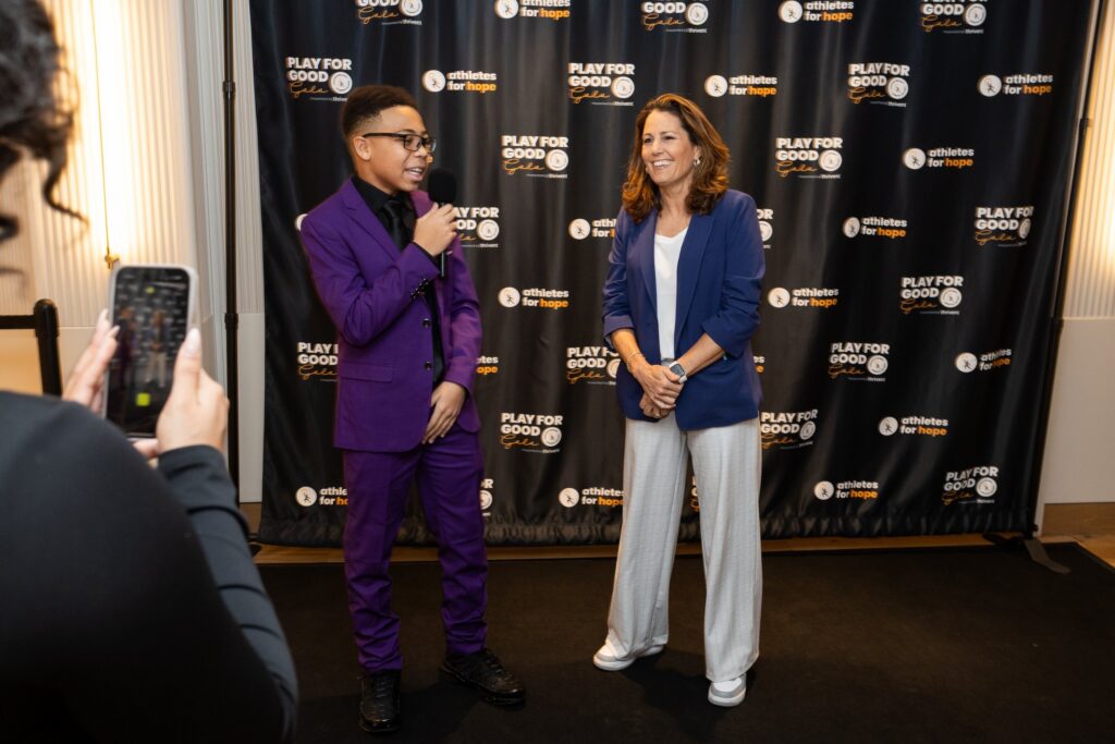 A woman is interviewed in front of the step-and-repeat at the 2025 Play for Good Gala