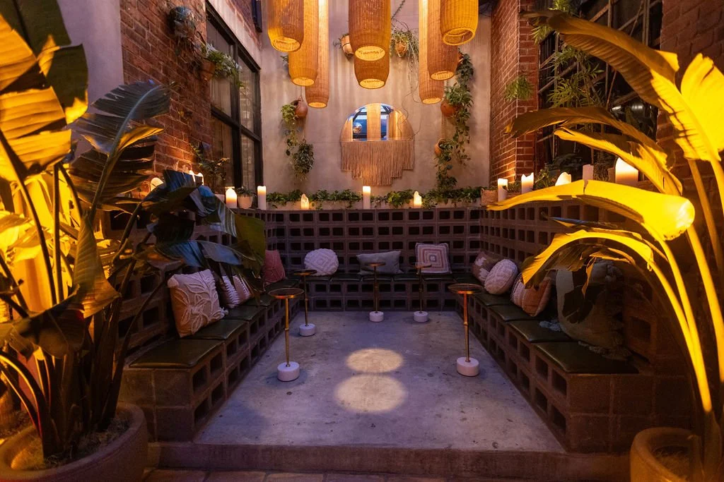 An inset seating area with eclectic throw cushions and small drink tables, lined with candles and plants