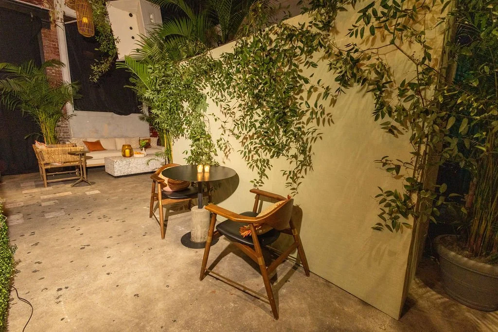 A small side table with two chairs beside a wall covered in greenery