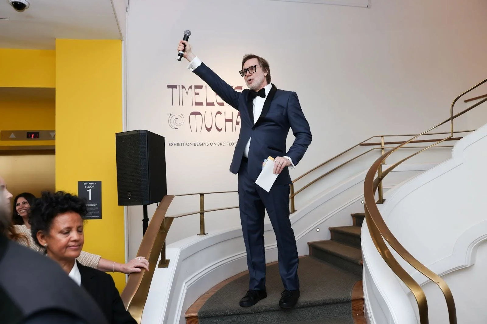 Man on staircase raising microphone in the air during a Stratus Firm produced event at The Phillips Collection In Washington, D.C.
