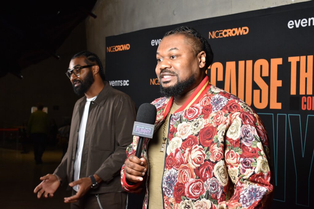 A man holds a mic at the 2025 "Because They're Funny" Comedy Festival