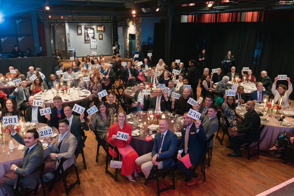 Event attendees hold up their bidding numbers at an auction during the Paths for Families Gala.