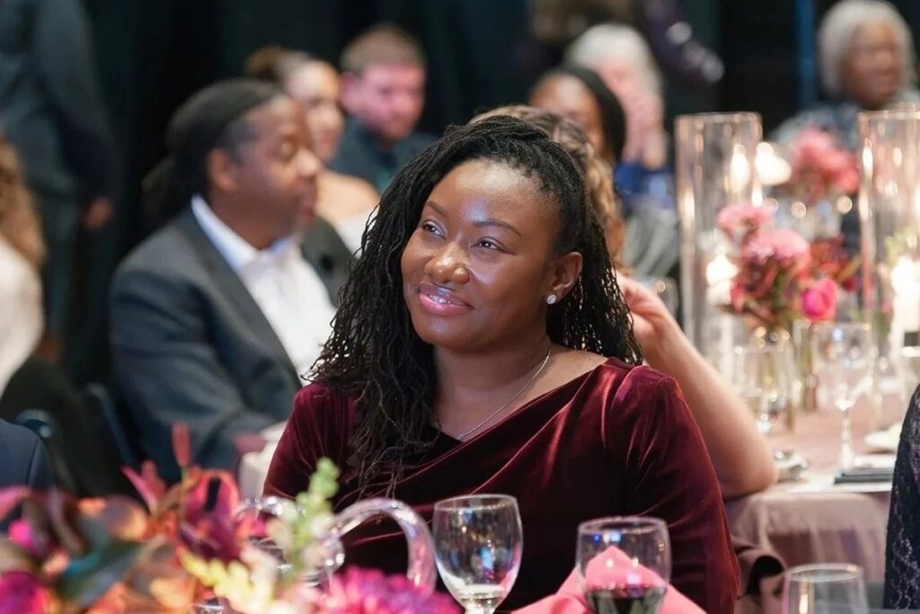 A woman smiling at an event, sitting at an elegantly-decorated table