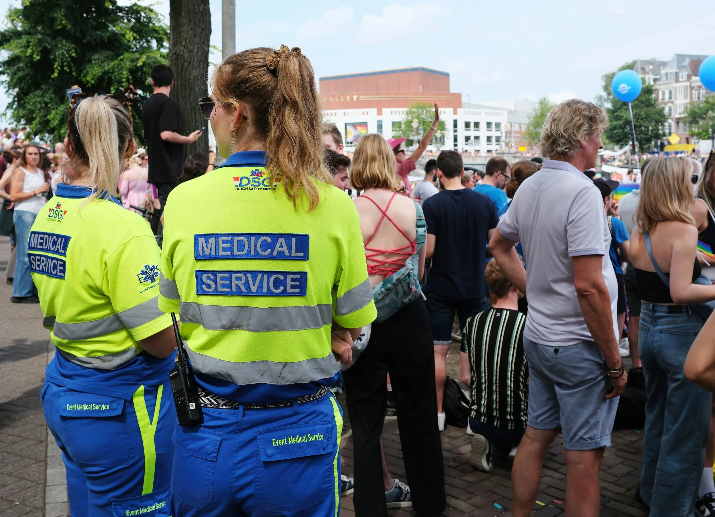 Event medical service providers stand near the back of the crowd at an outdoor event.