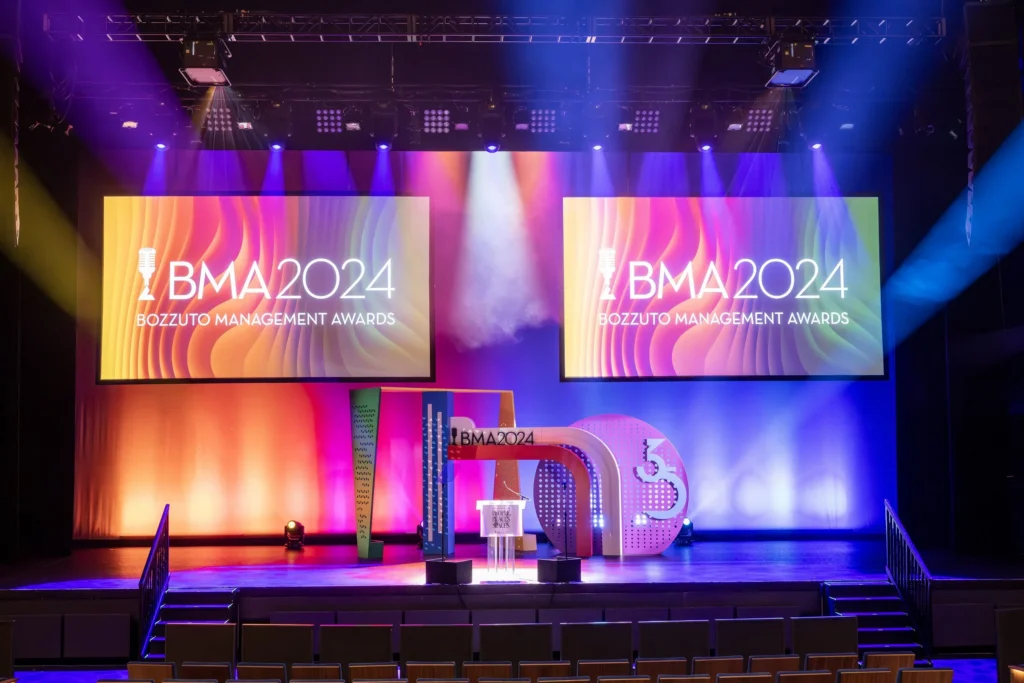 The empty stage at the 2024 Bozzuto Management Awards, with a podium and set pieces standing ready under two large screens.