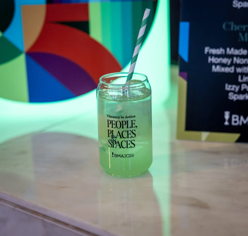 A colorful drink in a glass that reads "Vibrancy in Action: People, Places & Spaces — BMA 2024"