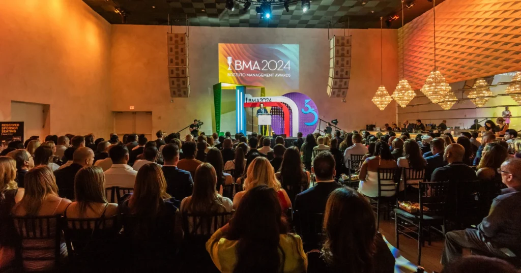 People sit in chairs watching a speaker onstage at the 2024 Bozzuto Management Awards