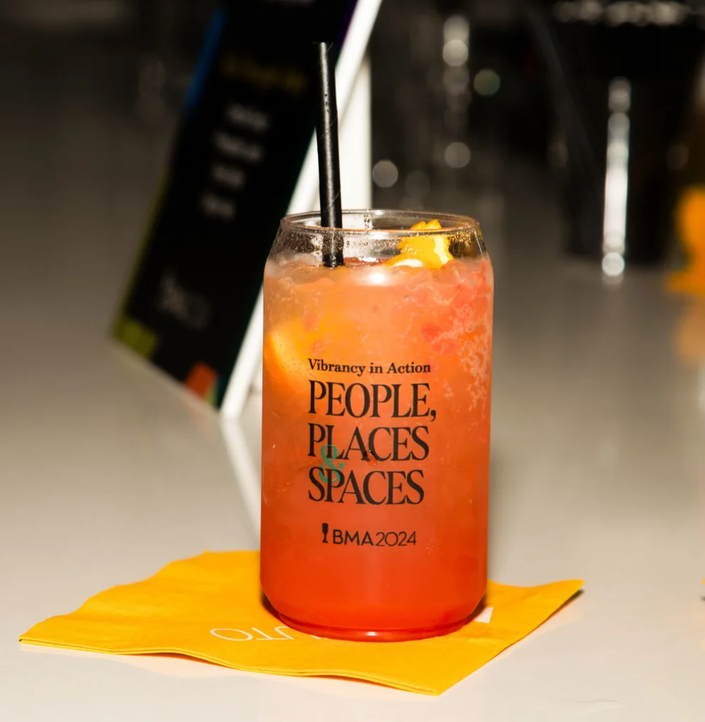 A colorful drink in a glass that reads "Vibrancy in Action: People, Places & Spaces — BMA 2024"