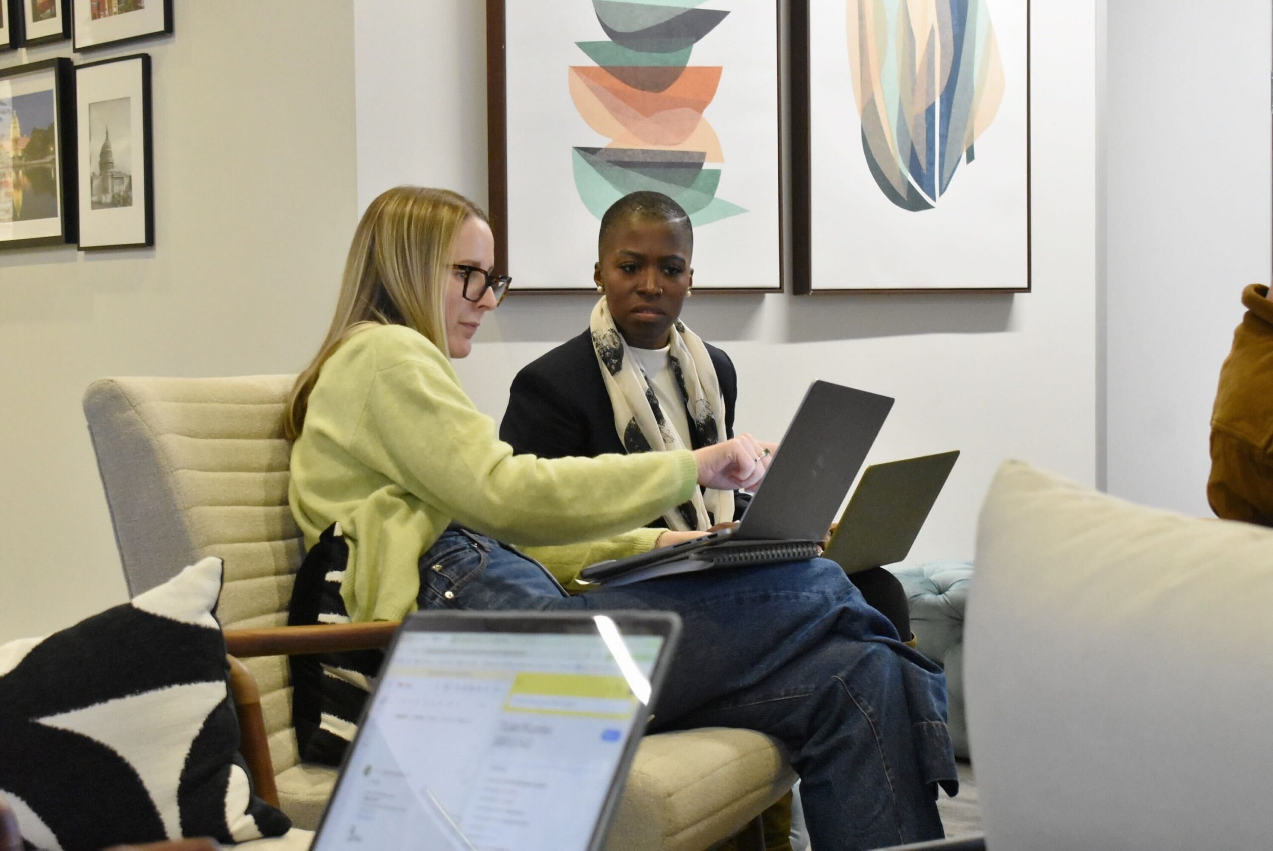 Two people look at laptops in an office
