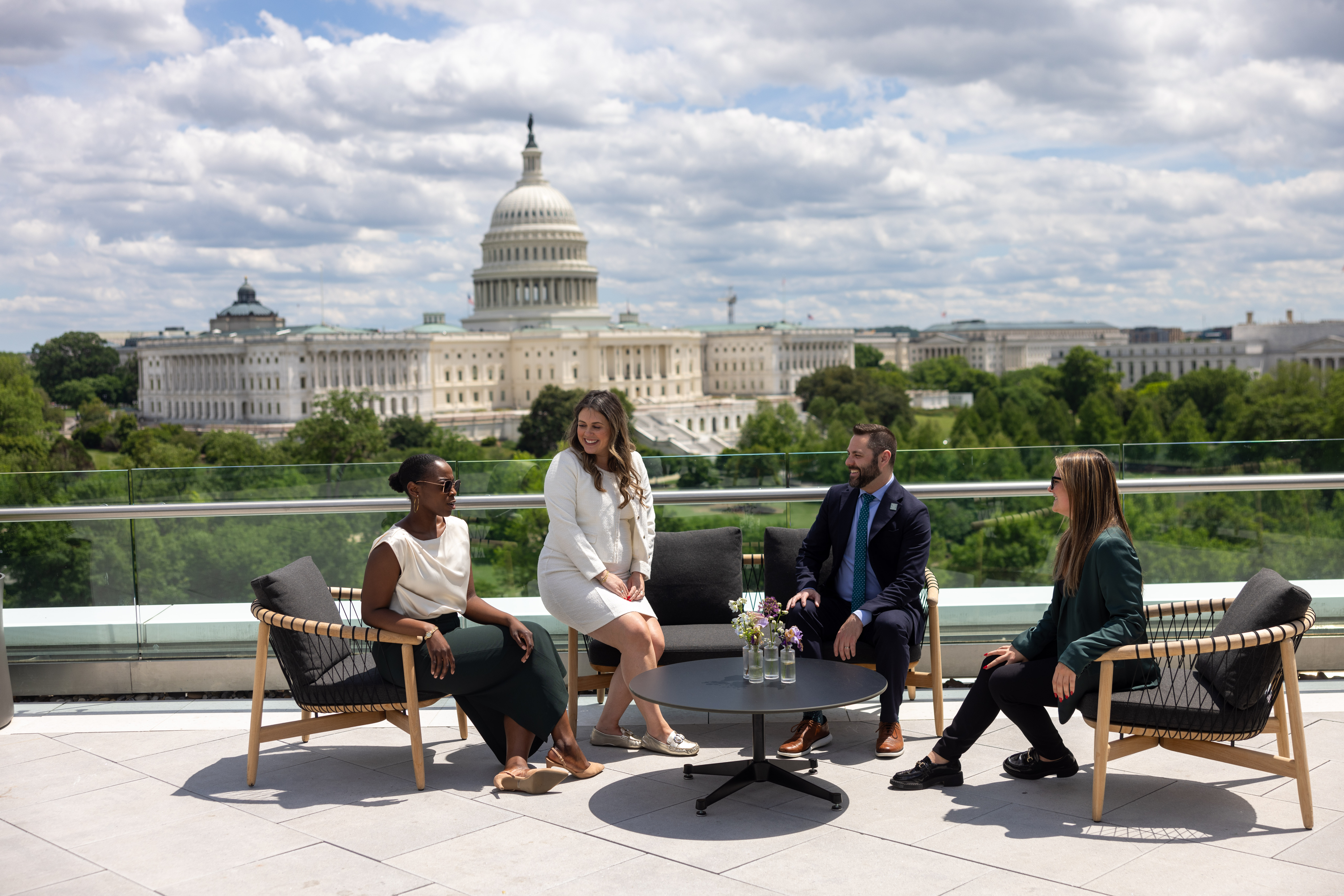 The Stratus Firm team sits outdoors on a patio with the U.S. Capitol Building in the background.