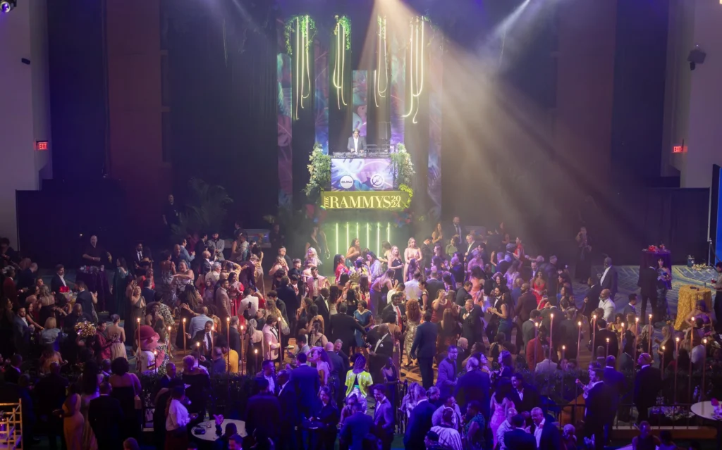 Lights shine down on event attendees dancing, eating, and mingling at the 2024 RAMMY Awards.