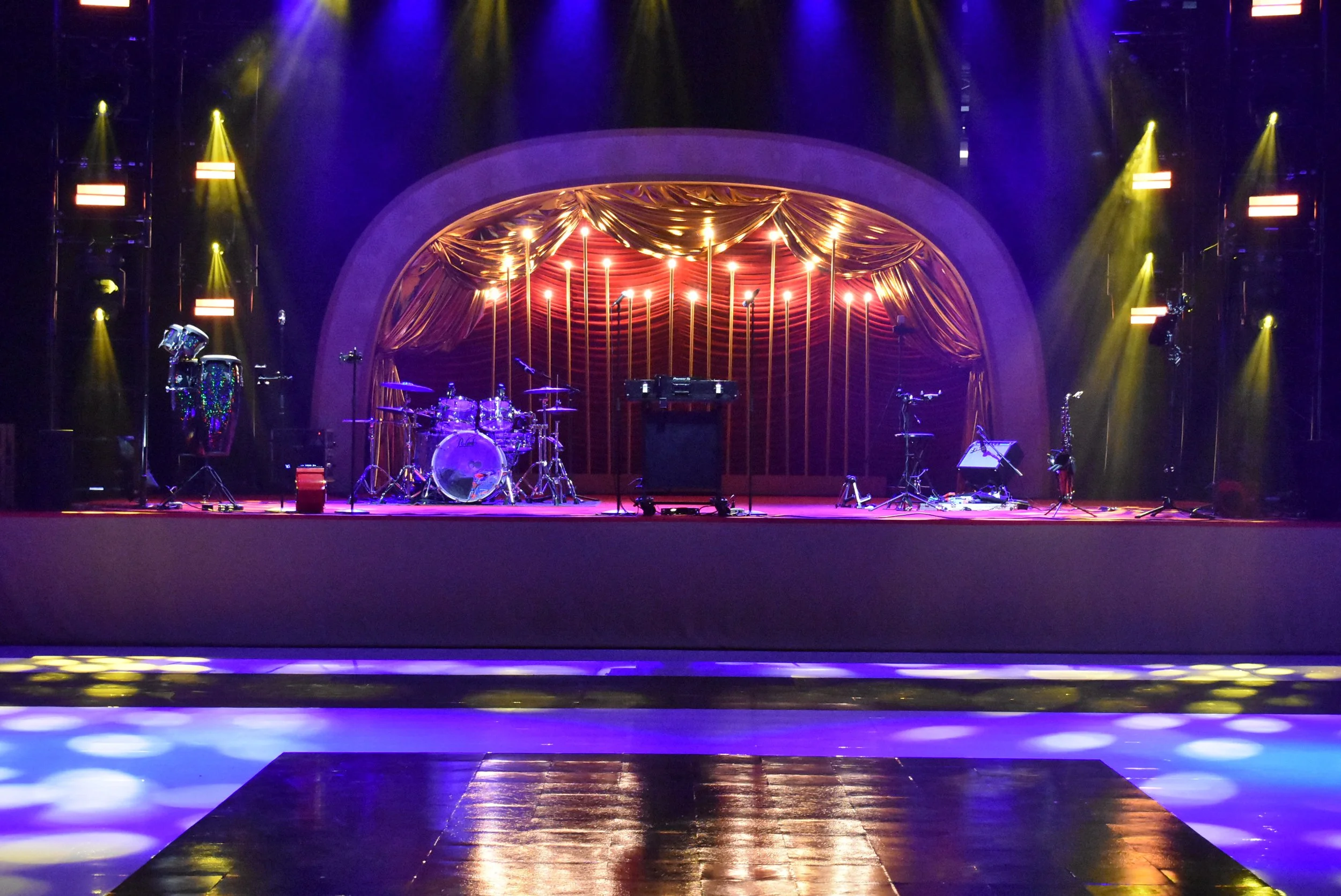 A stage with instruments waiting on it, bathed in blue and yellow light.
