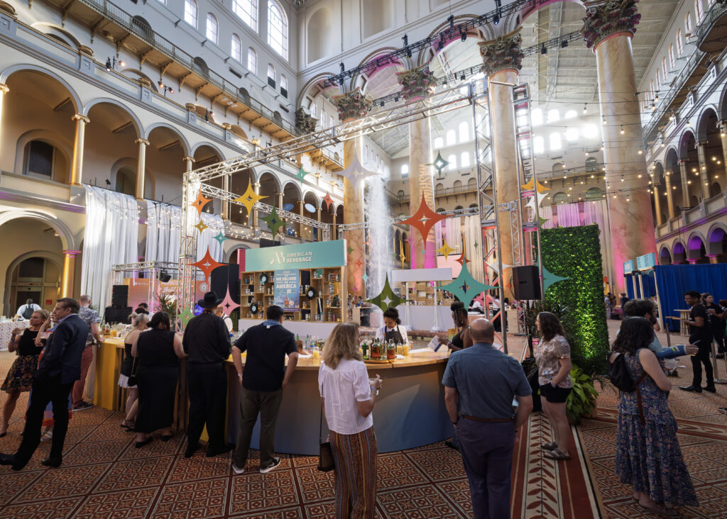 Event attendees mingle around the bar and throughout the event space.