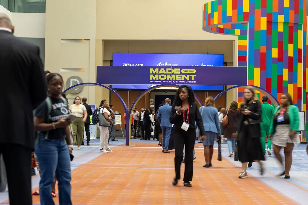 Event attendees move smoothly between rooms in a building with colorful signage.