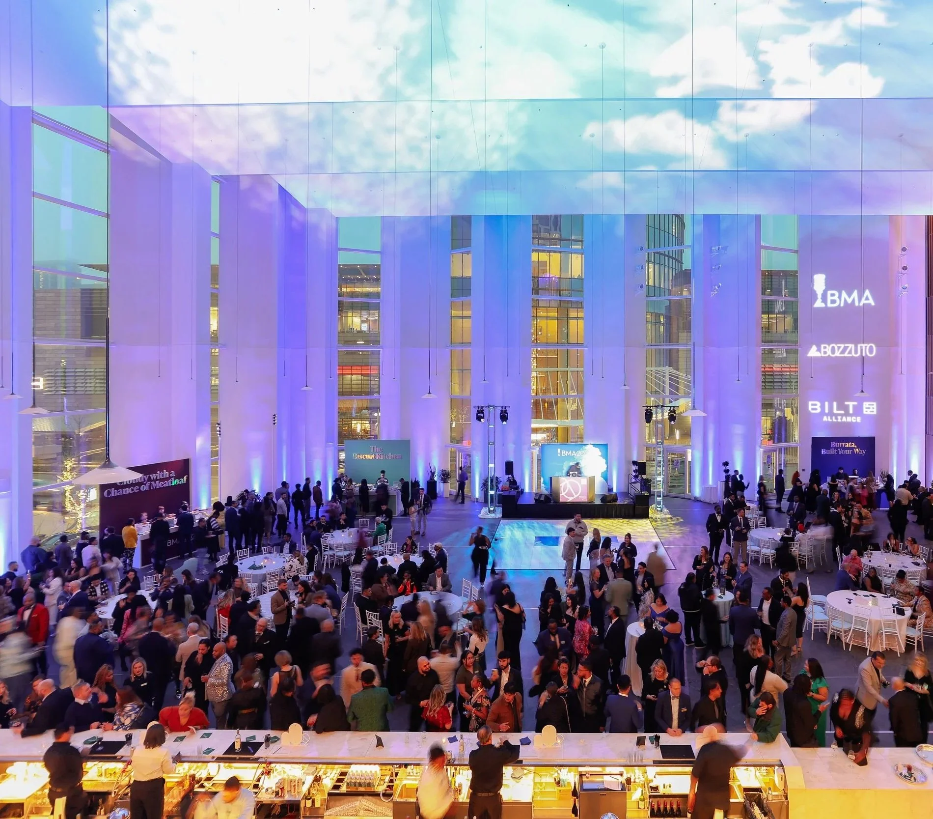 Event attendees mingle in the dining room at the BMAs, moving between stations with labels like "Cloudy with a Chance of Meatloaf," "The Biscuit Kitchen," and "Burrata, Built Your Way."