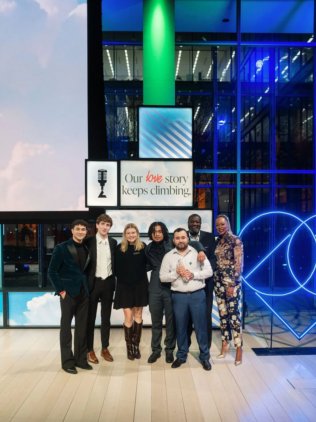 A group of people pose together under the signage at the BMAs.